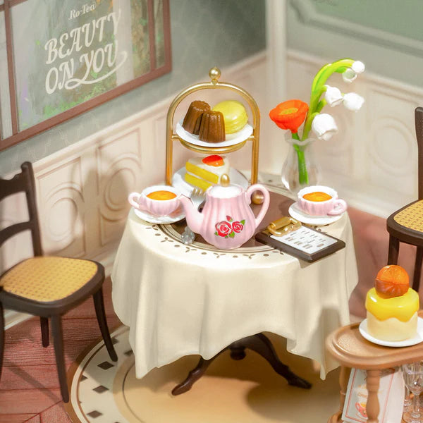 Sweet Sips Tea DIY Miniature House with cakes on a table in a cozy room setting.