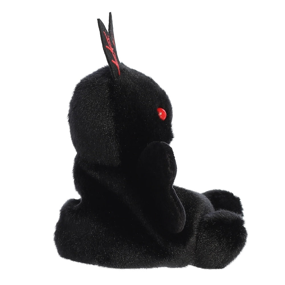 Black plush toy with red eyes on a white background