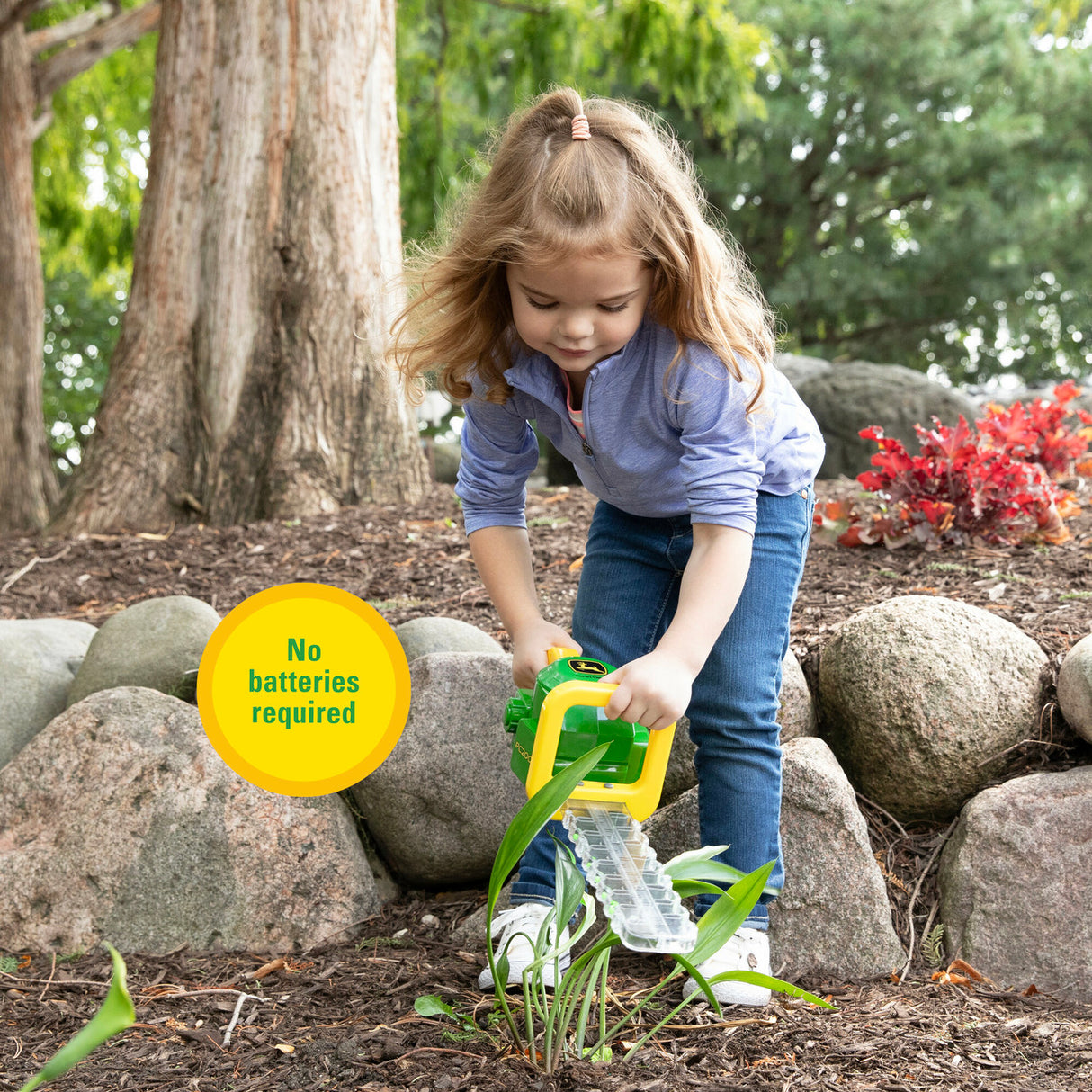 Child playing with a John Deere Hedge Trimmer Toy in a natural setting