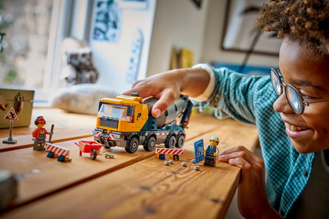 Child playing with LEGO City Great Vehicles: Cement Mixer on a wooden table
