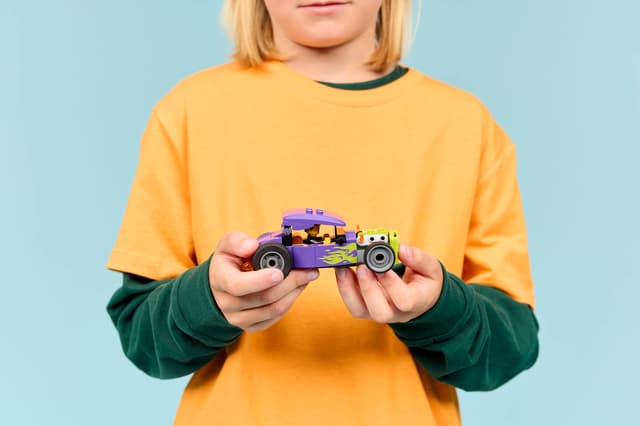 Child holding a LEGO City Great Vehicles: Hot Rod on a blue background