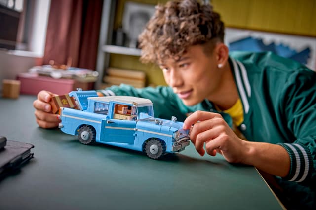 Child playing with a blue LEGO Harry Potter: Enchanted Flying Ford Anglia™ in a room setting