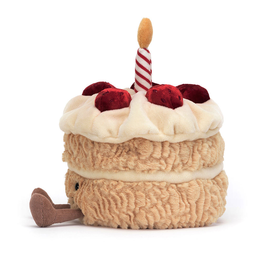 Plush toy designed to look like a layered birthday cake with cream and red cherries on top, featuring a striped candle and a small attached legs, named Amuseables Birthday Cake.