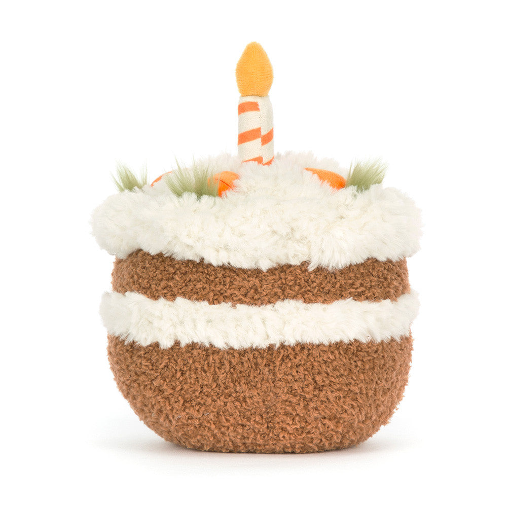 Soft plush Amuseables Carrot Cake toy designed to look like a layered birthday cake with white frosting, carrots, greenery accents, and a striped candle on top.
