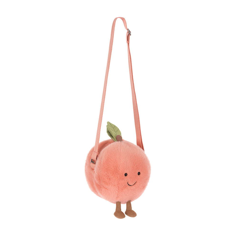 Amuseables Peach Shoulder Bag is a soft, plush peach-shaped bag with a smiling face, small feet, a green leaf detail, and an adjustable peach-colored shoulder strap.