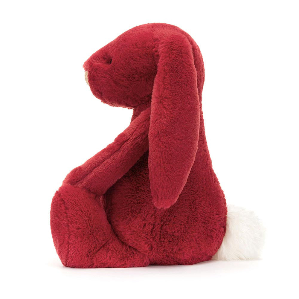 Side view of a plush deep red stuffed bunny with long floppy ears and a fluffy white tail, called Bashful Luxe Bunny Scarlett Huge, designed as a soft toy for kids.