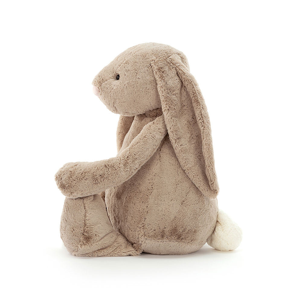 Soft plush beige bunny with long floppy ears and a fluffy white tail, shown sitting sideways, Bashful Beige Bunny Large stuffed animal perfect for children’s play and comfort.