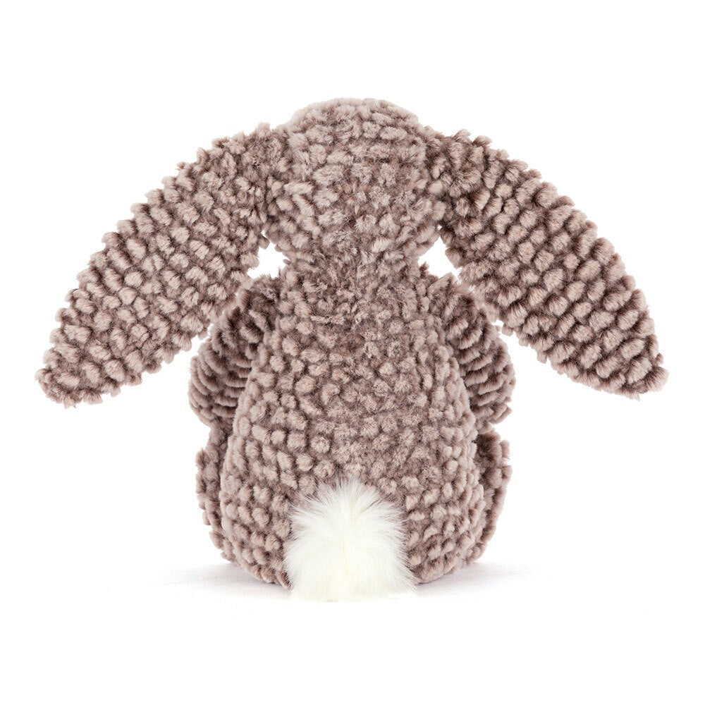 Bashful Luxe Bunny Pine plush toy shown from the back, featuring soft textured brown fabric with long ears and a fluffy white tail.