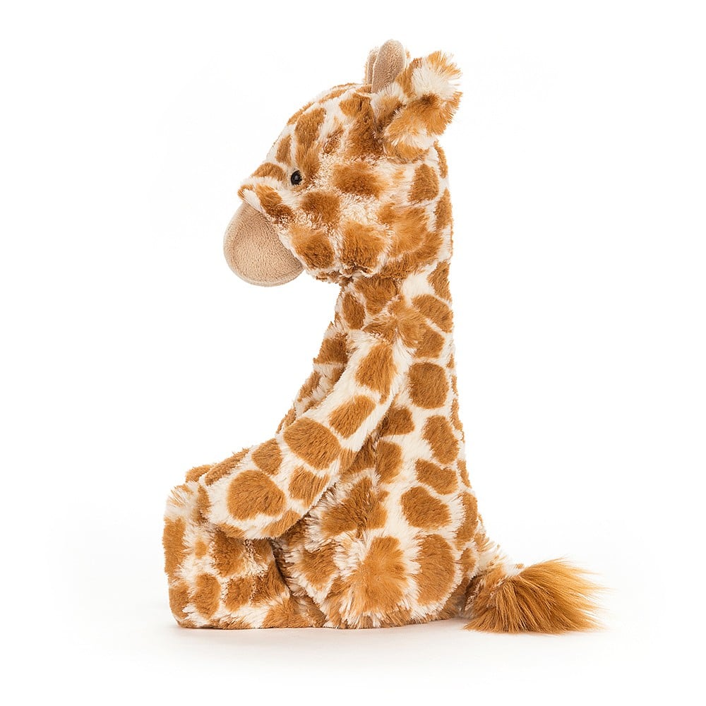 Bashful Giraffe plush toy sitting upright with soft brown and cream spotted fur, detailed face, and a fluffy tail.