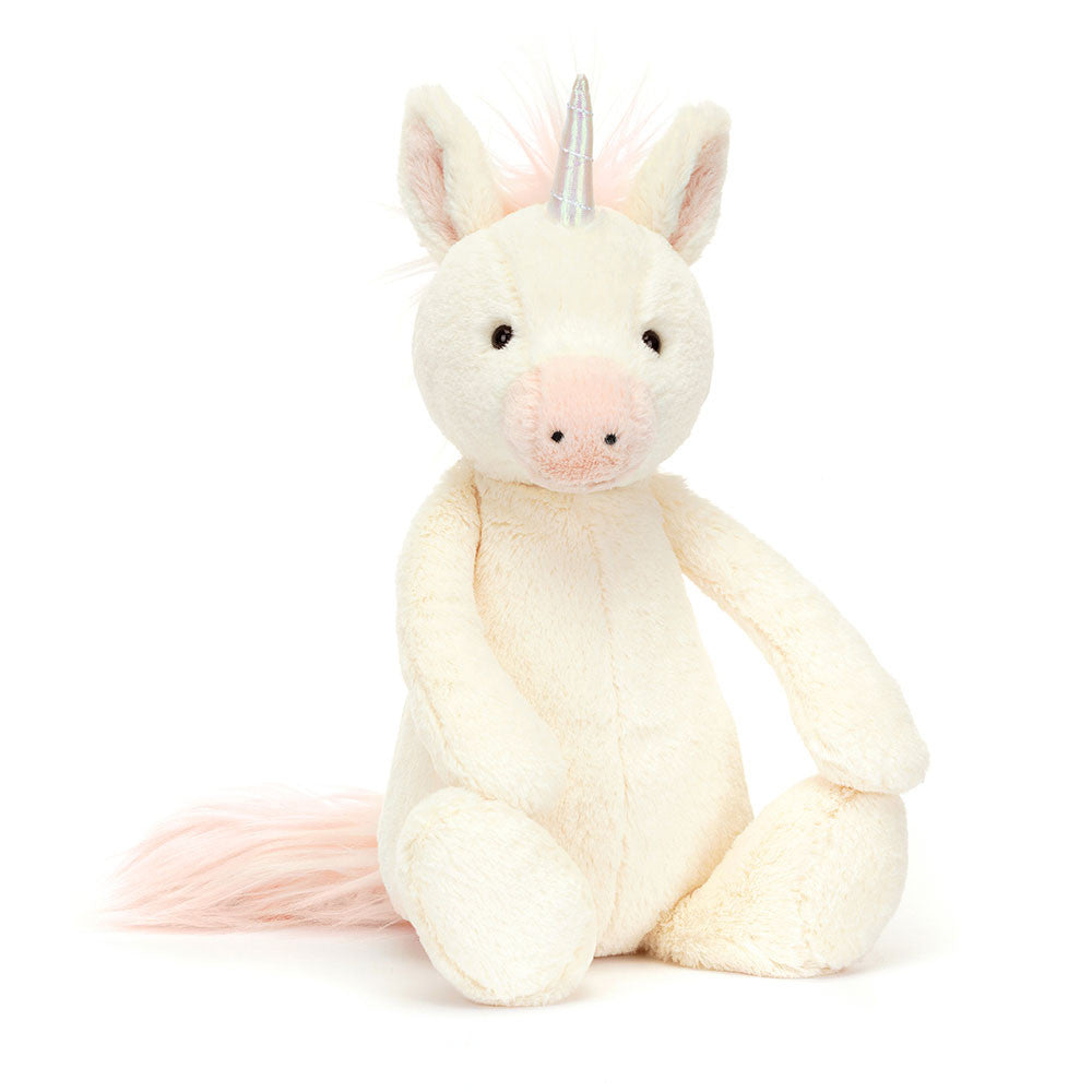 Bashful Unicorn Medium plush toy with a soft cream-colored body, light pink accents on the snout and tail, and a shiny silver horn, sitting upright on a white background.
