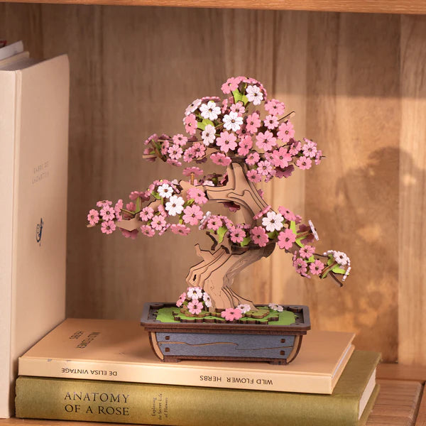 Sakura Bonsai DIY Wooden 3D Puzzle on top of books with a wooden shelf background