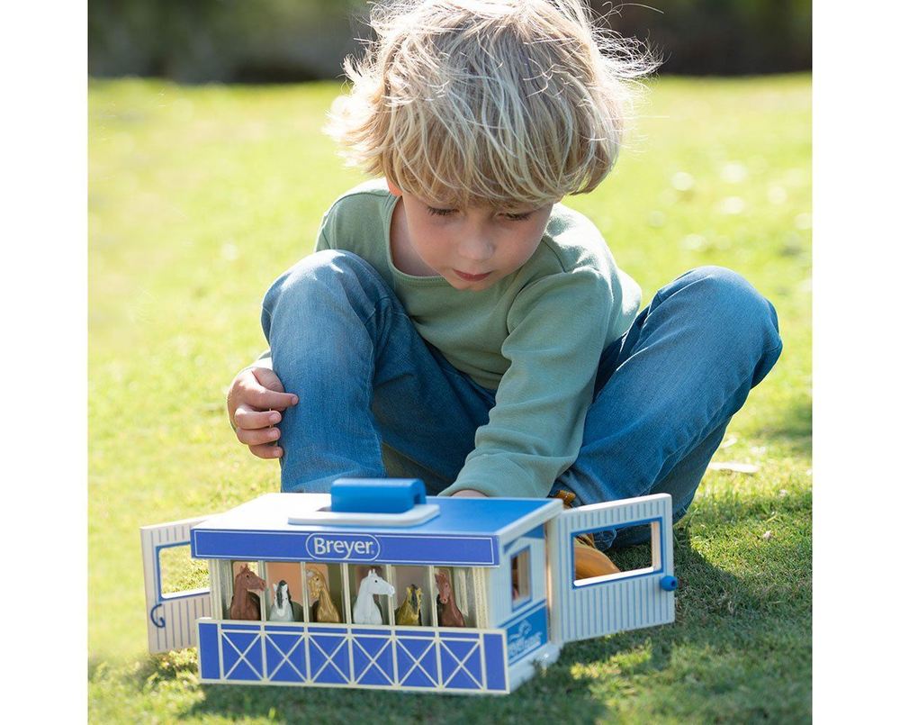 Child playing with a toy stable set on grass