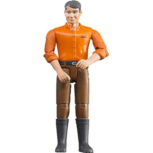 Plastic toy figure of a man, light skin, brown jeans, wearing an orange button-up shirt and black boots, standing upright with folded arms.