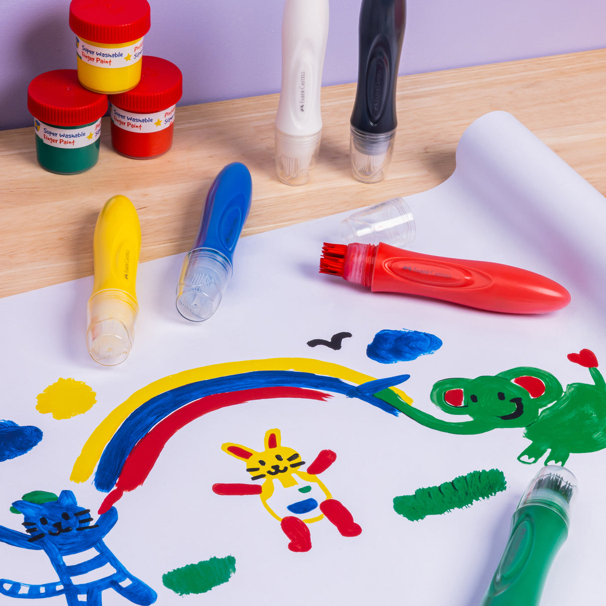 Colorful children's drawings on paper with Little Creatives 6 Jumbo Washable Squeeze Paintbrushes and paint containers.