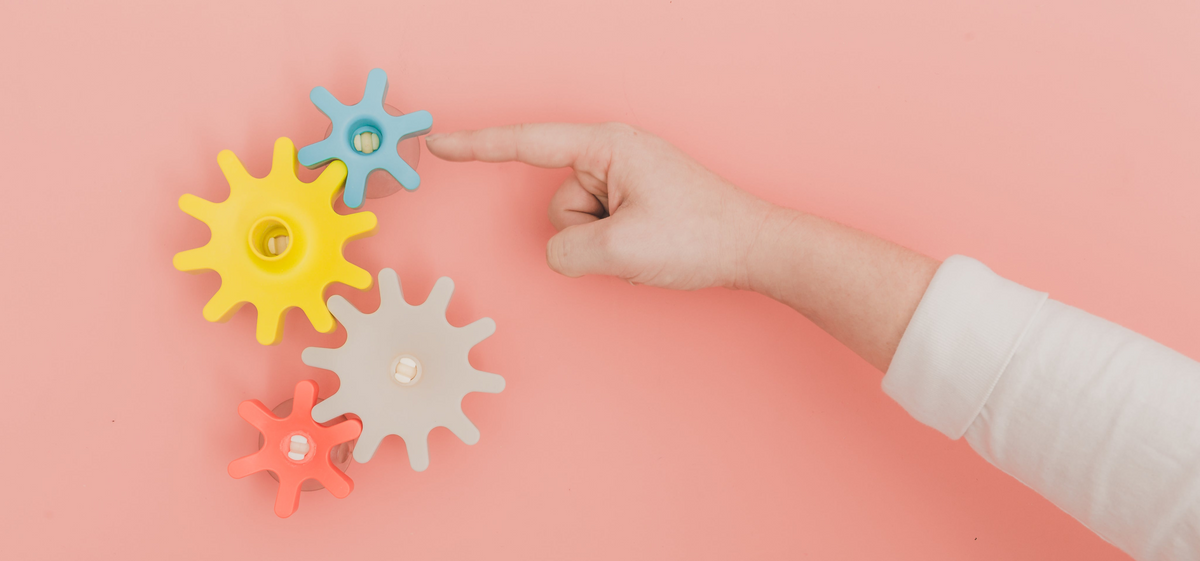 finger turning gears on pink background