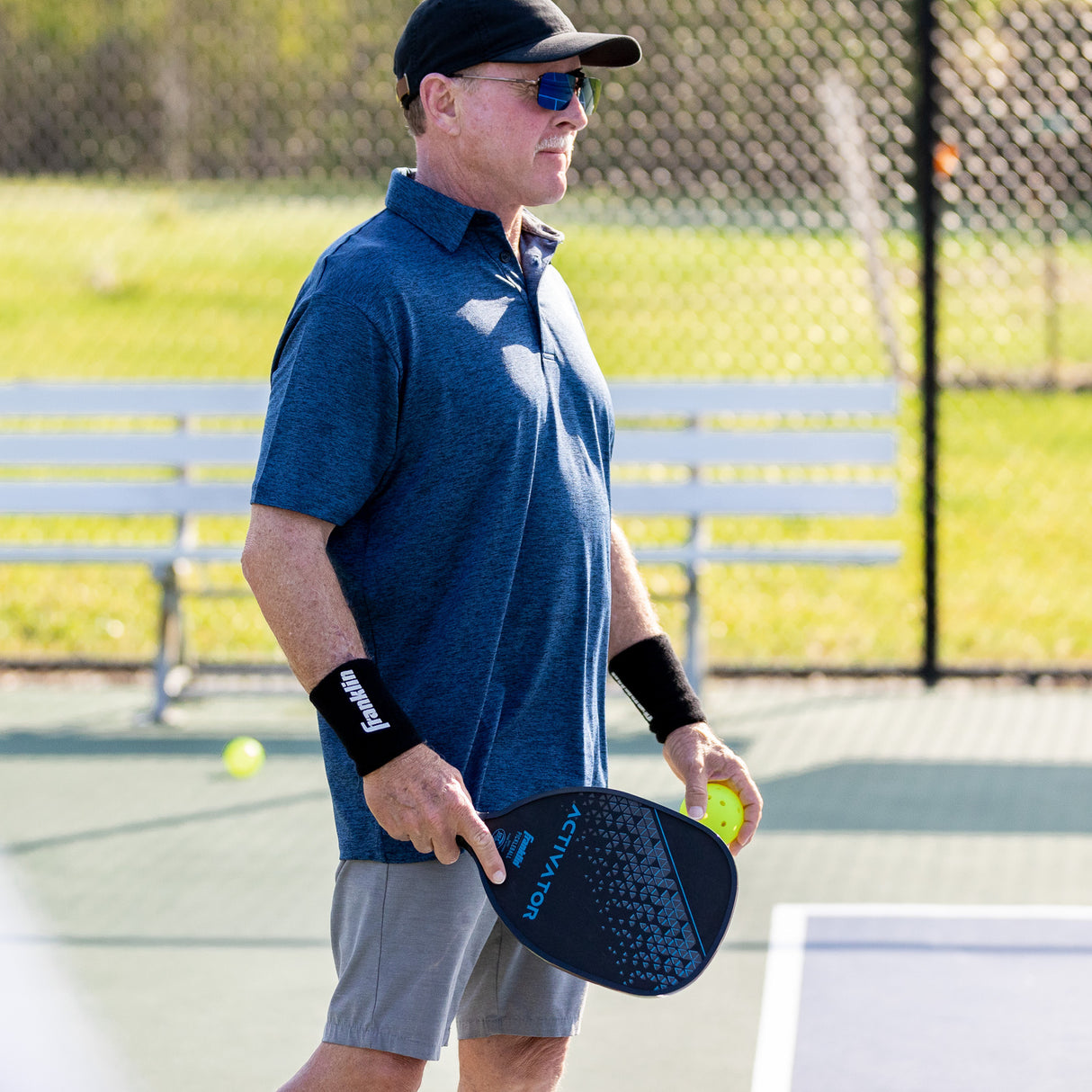 Man holding a pickleball paddle and ball on a court