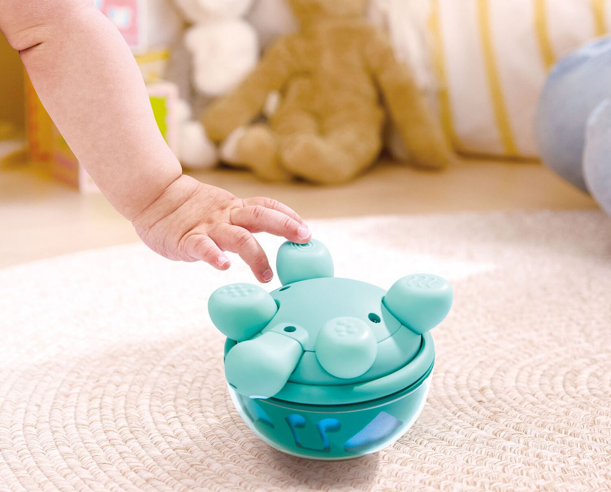 Child's hand interacting with a Twist & Tune Turtle toy on a carpeted floor.