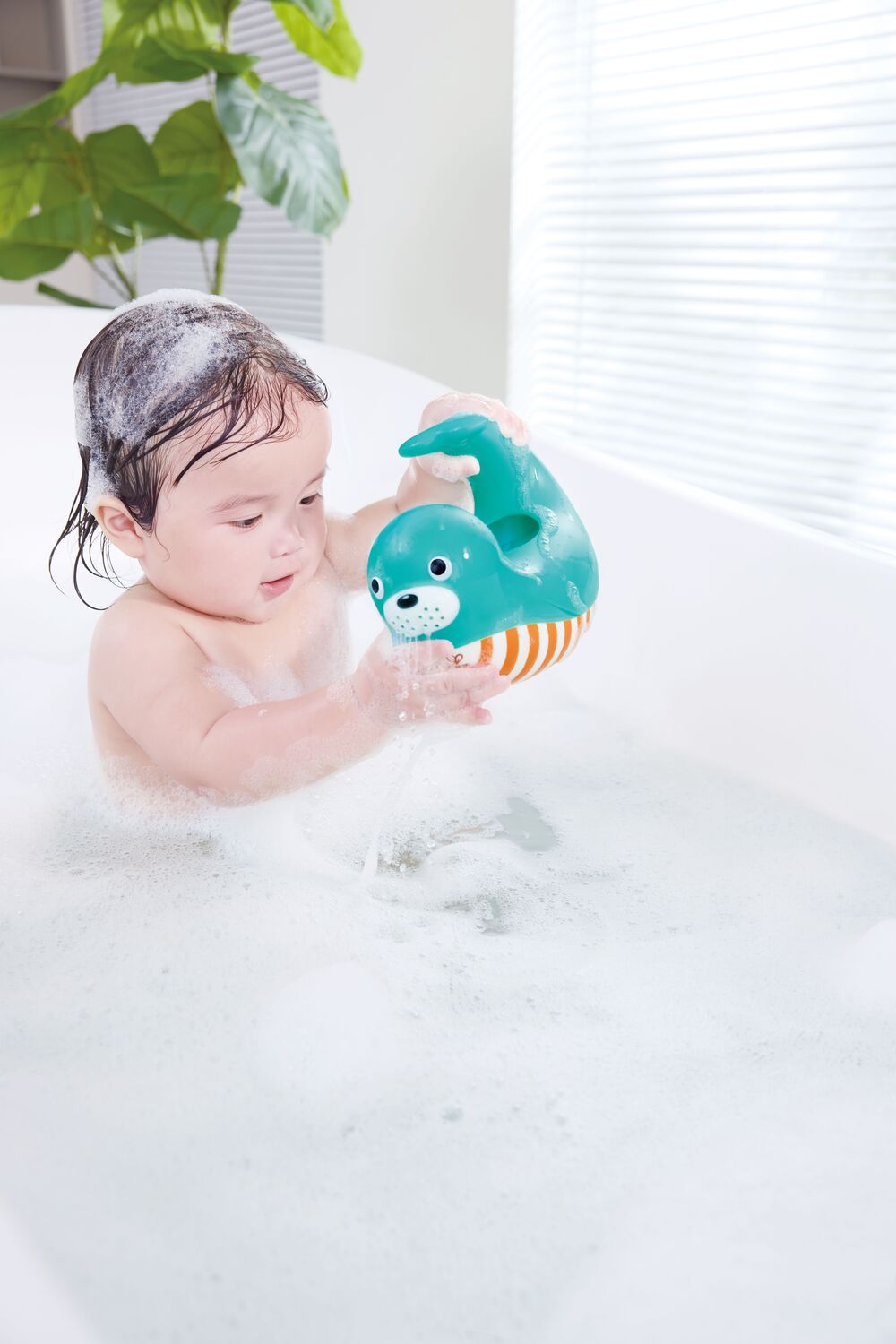 Child playing with a Happy Splashers Seal Jug in a bubble bath