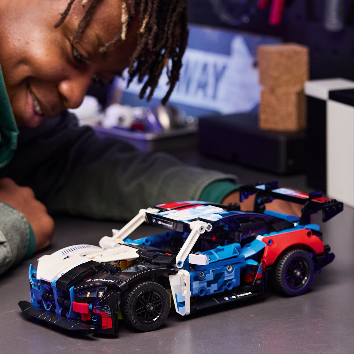 Child playing with a LEGO Technic: BMW M4 GT3 EVO Race Car toy model on a table.