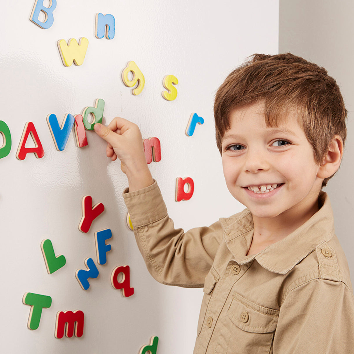 Child playing with colorful magnetic letters on a white board