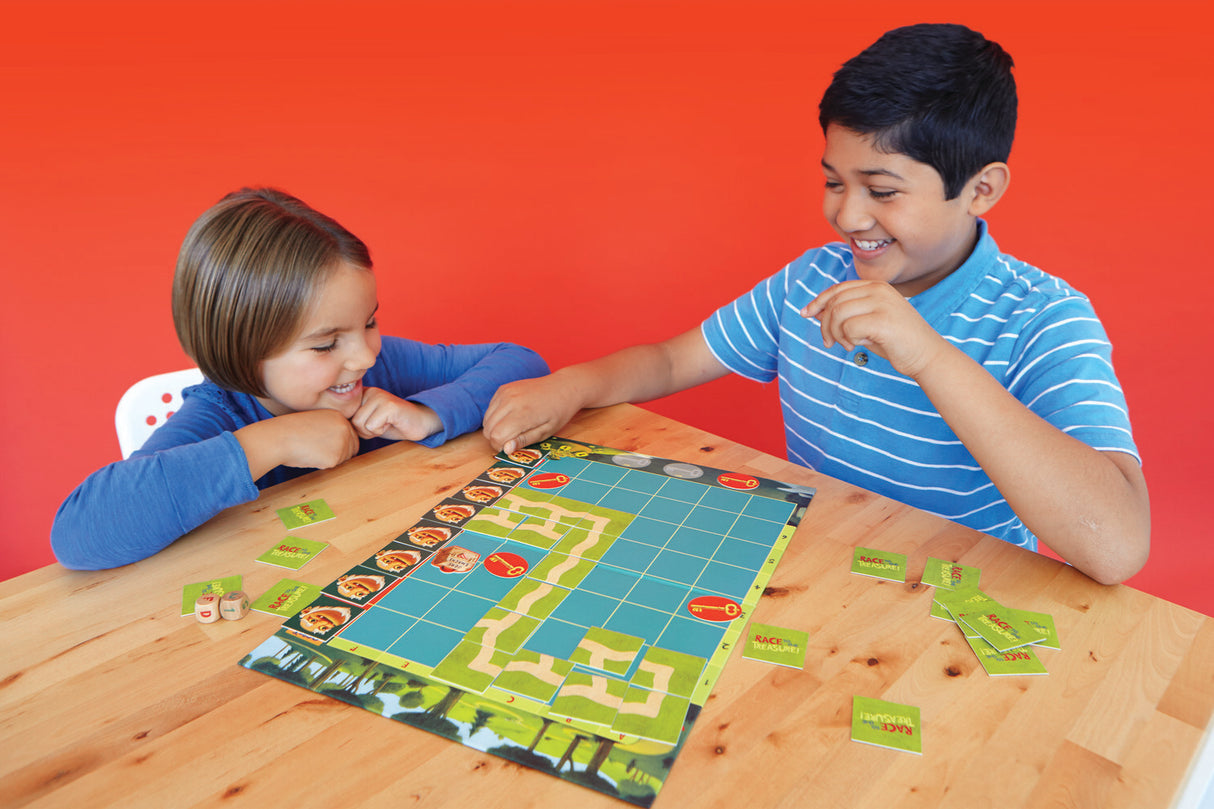Two children playing Race To The Treasure Cooperative board game on a wooden table with a red background