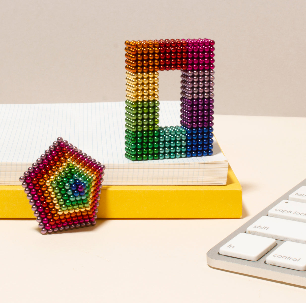 Colorful Spectrum Speks sculptures on a desk with a keyboard and books in the background.