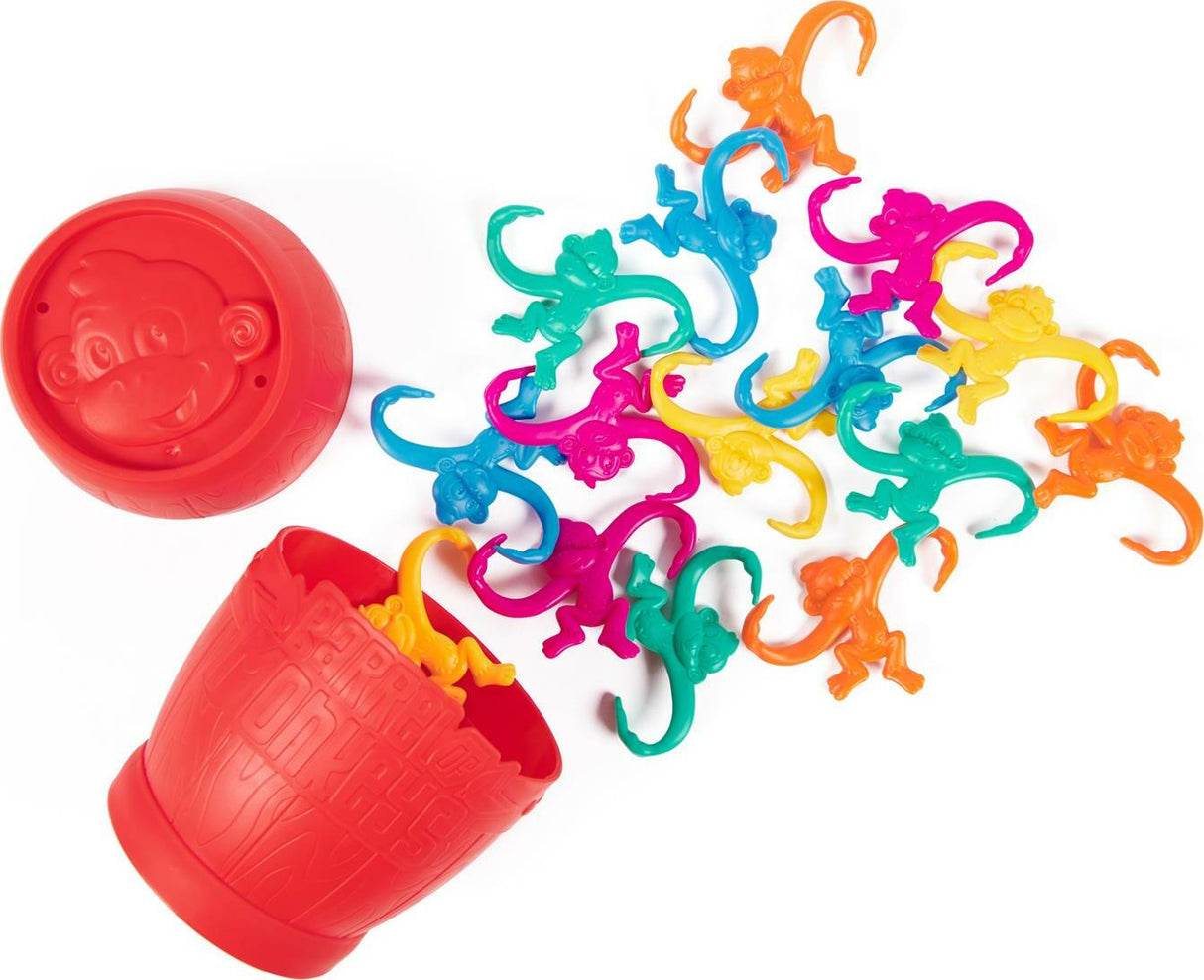 Colorful plastic monkeys spilling out of a red container on a white background