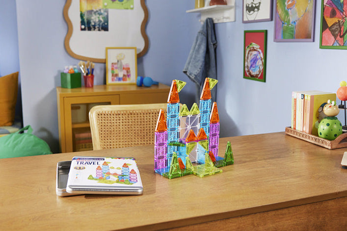 Colorful Magna-Tiles microMags Travel Deluxe 55 Piece Set on a wooden table with a child's room in the background.