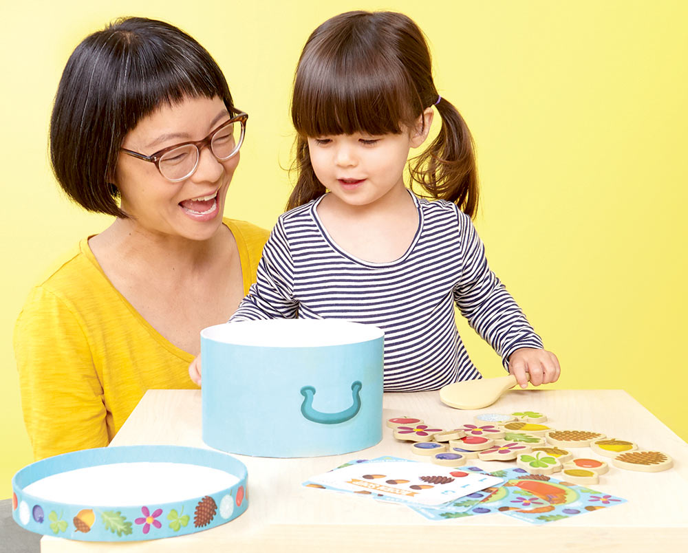 Woman and child playing Acorn Soup The Tasty Counting Game at a table against a yellow background