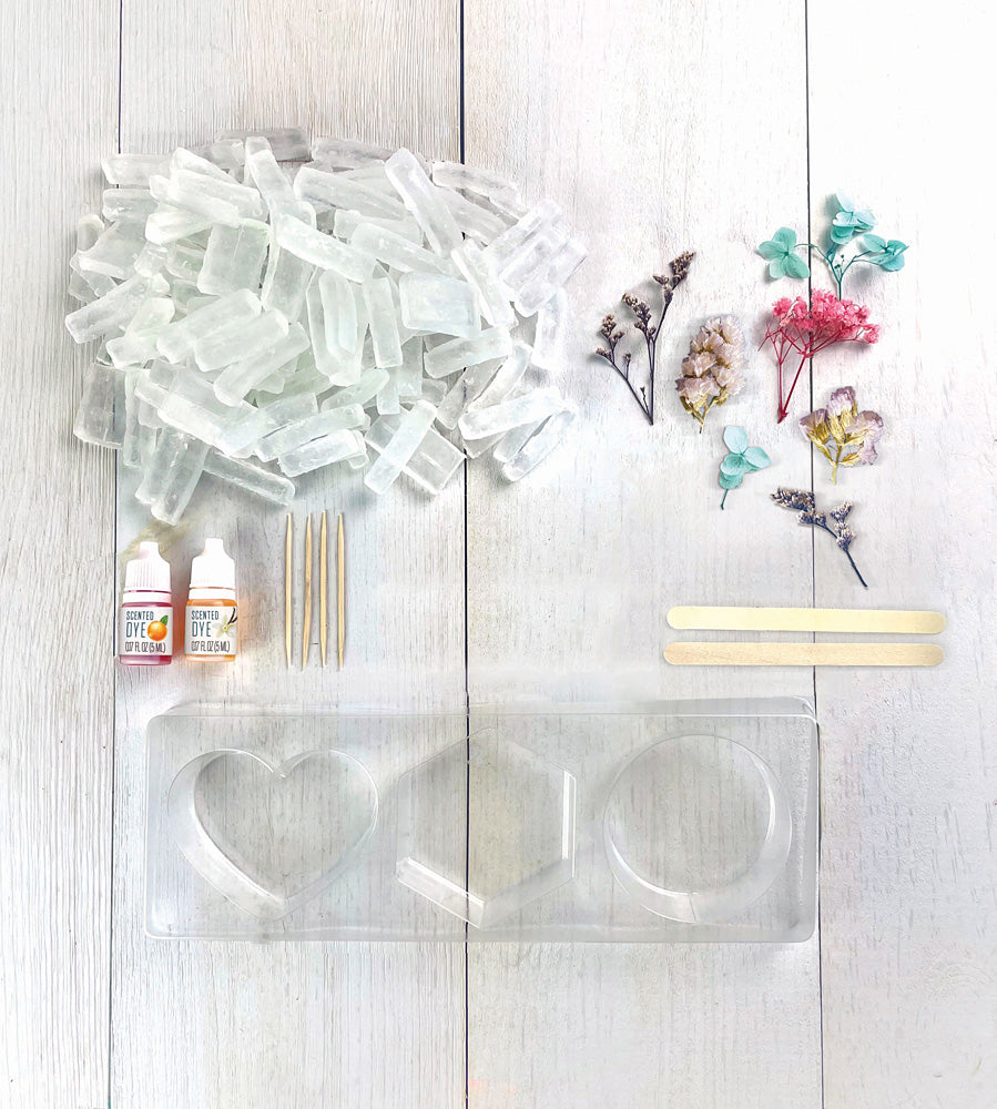 Set of clear silicone molds, bottles, and floral decorations for Wish*Craft Flower Power DIY Soap kit on a light wooden surface