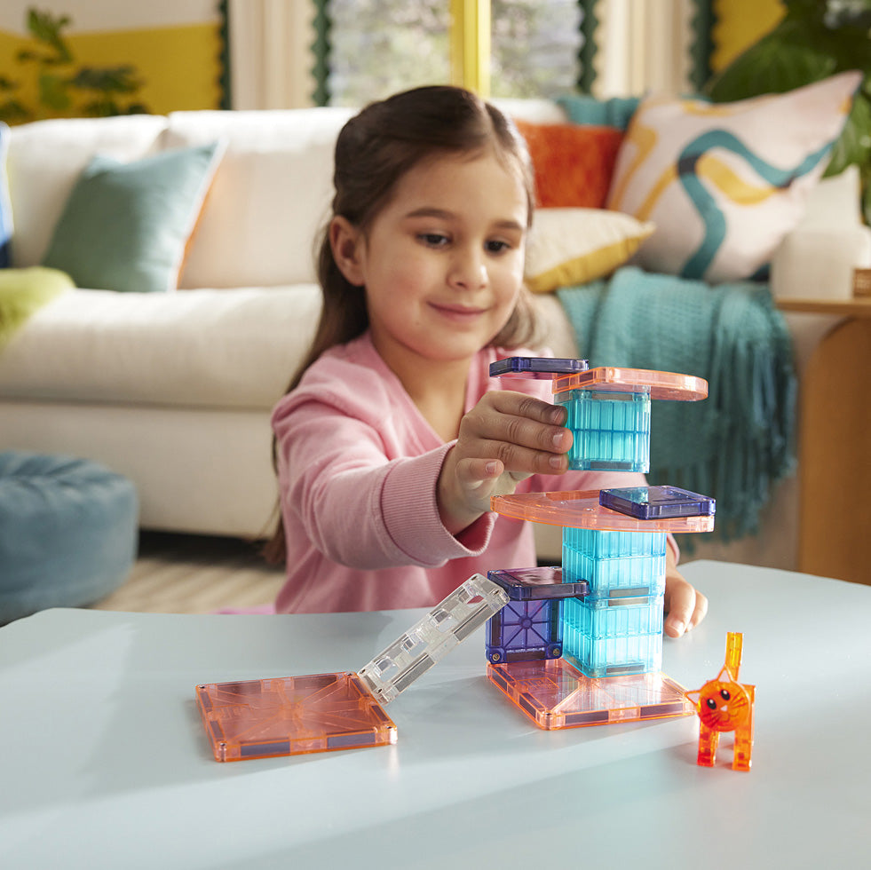 Child playing with Magna-Tiles Cat Tree 13 Piece Set on a table in a living room.