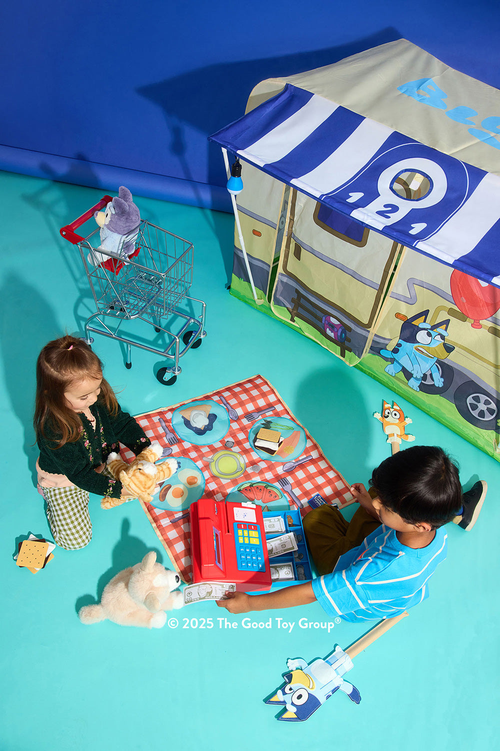 Two children playing with toys in front of a Bluey Camping Activity Fort.
