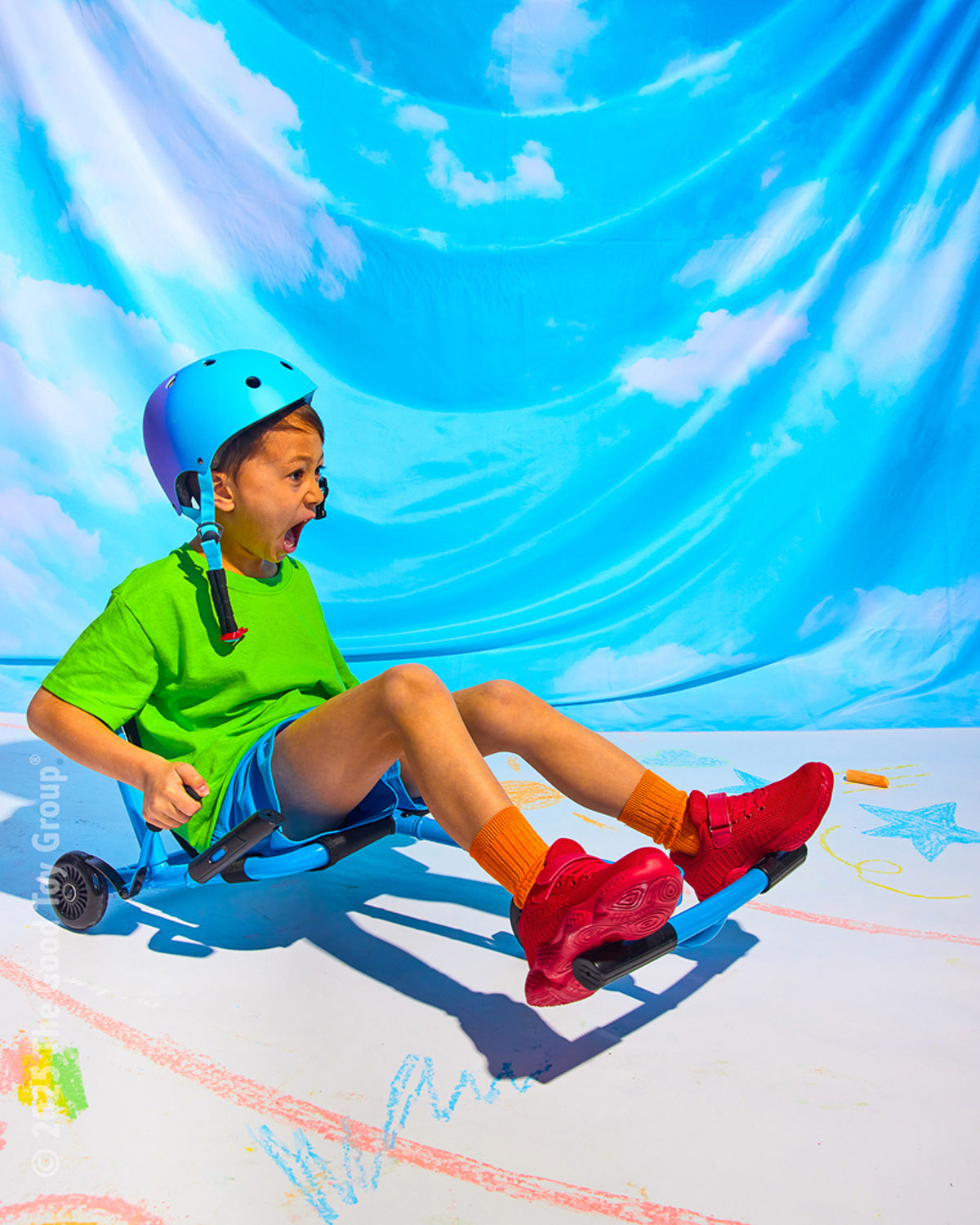 Child riding a EzyRoller Classic - Bluewith a blue helmet against a bright blue sky backdrop