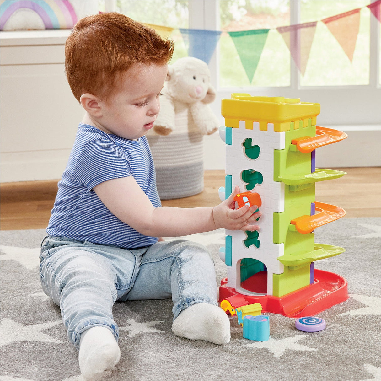 Child playing with a Kidoozie Drop 'n Roll Activity Tower on a carpeted floor.