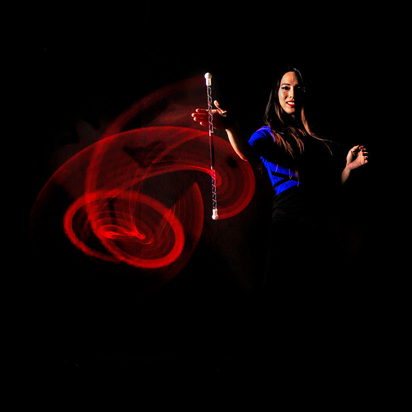 Woman holding a Wandini Glow.0 Magic LED Levitation Wand with red and blue light trails against a black background