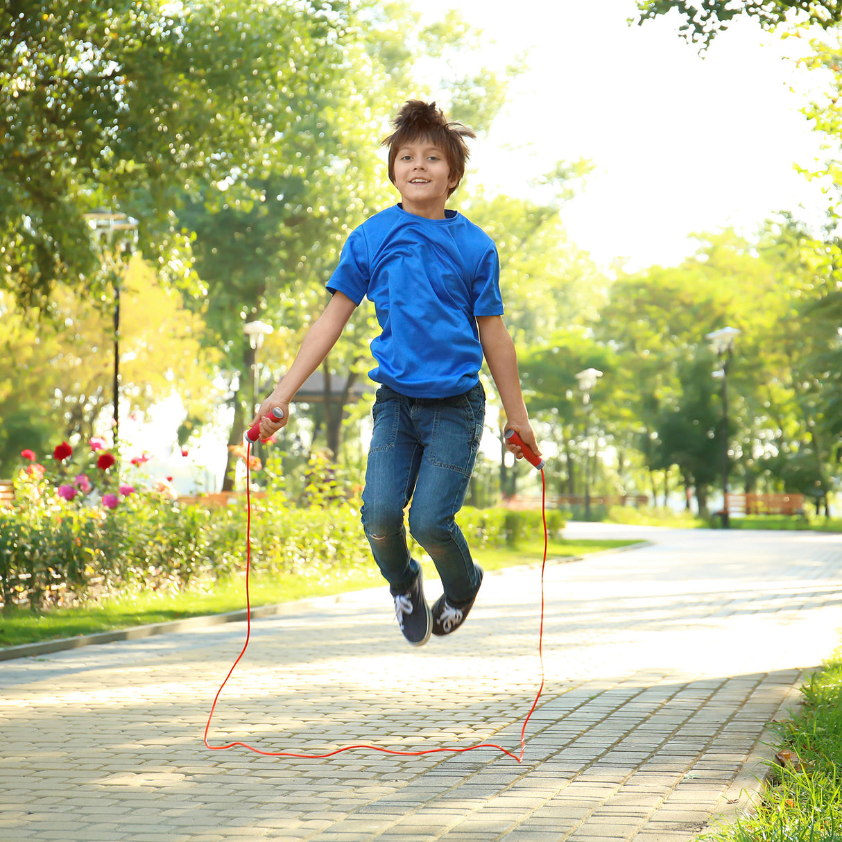 Child jumping rope in a park with trees and flowers in the background