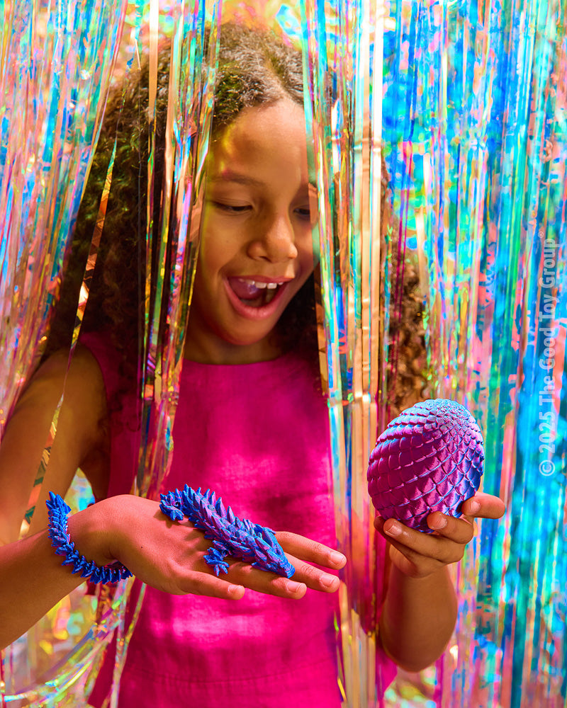 Child holding purple Twiddle Sensory Dragon! in front of colorful tinsel