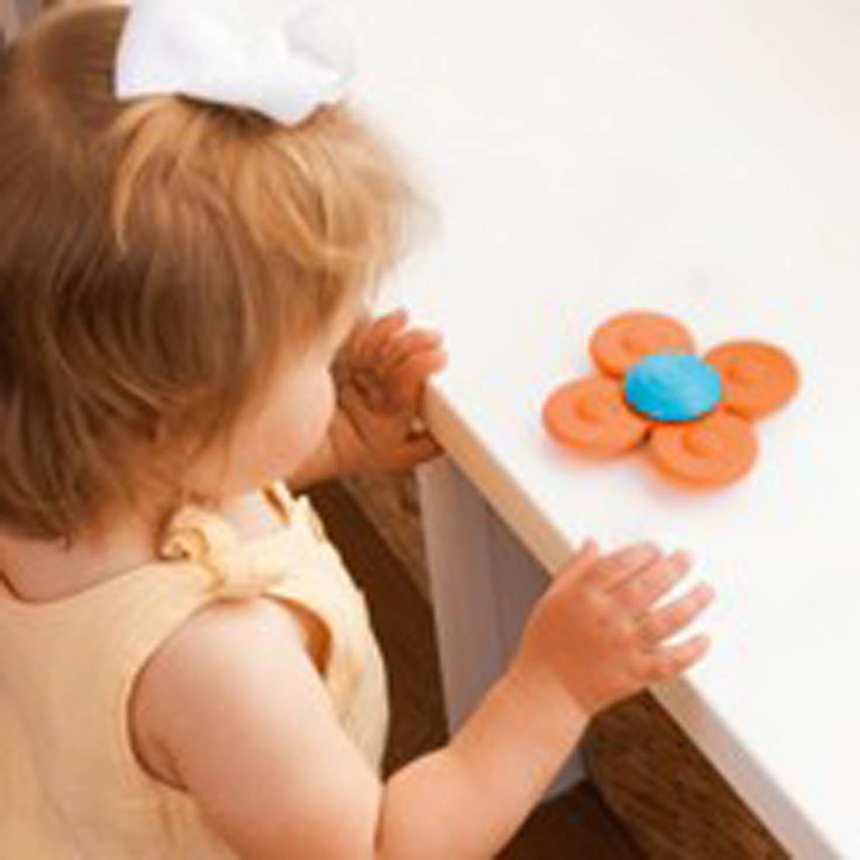 Child interacting with a Whirly Squigz Fun Little Spinner! Single toy on a white surface