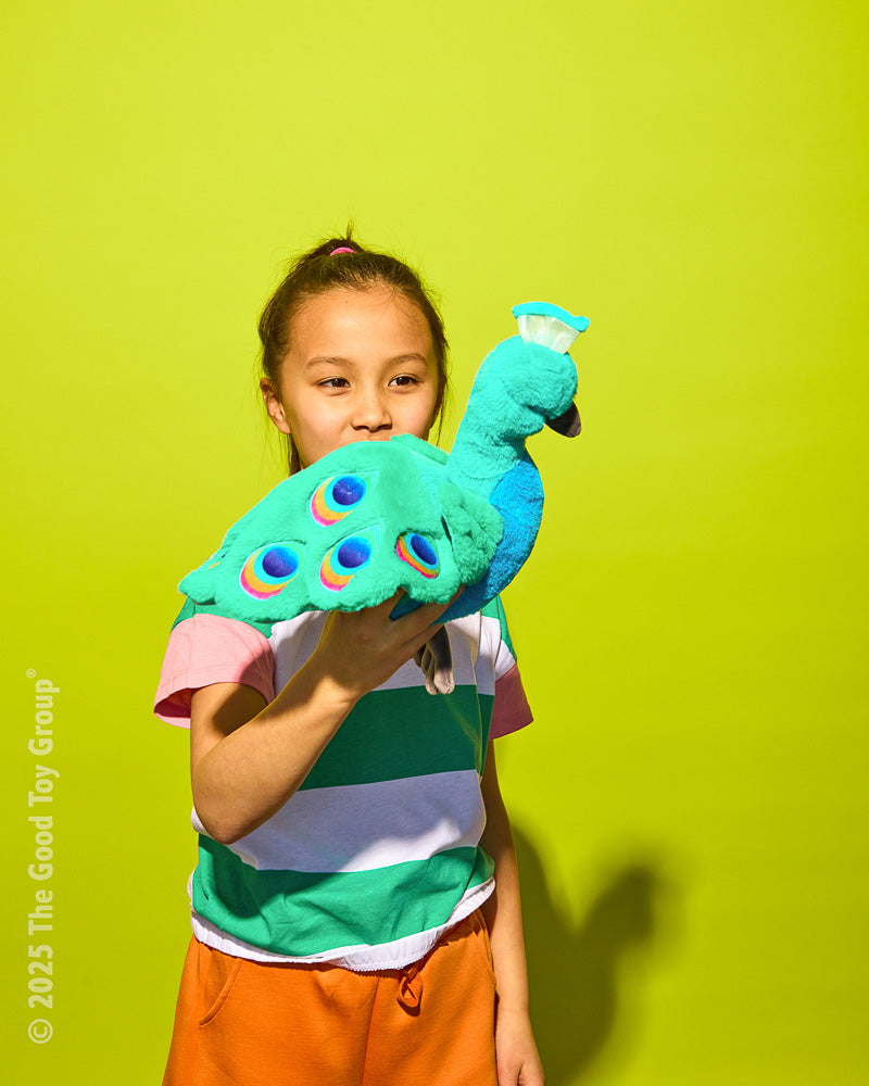 Girl holding plush Pattie Peacock on a green background