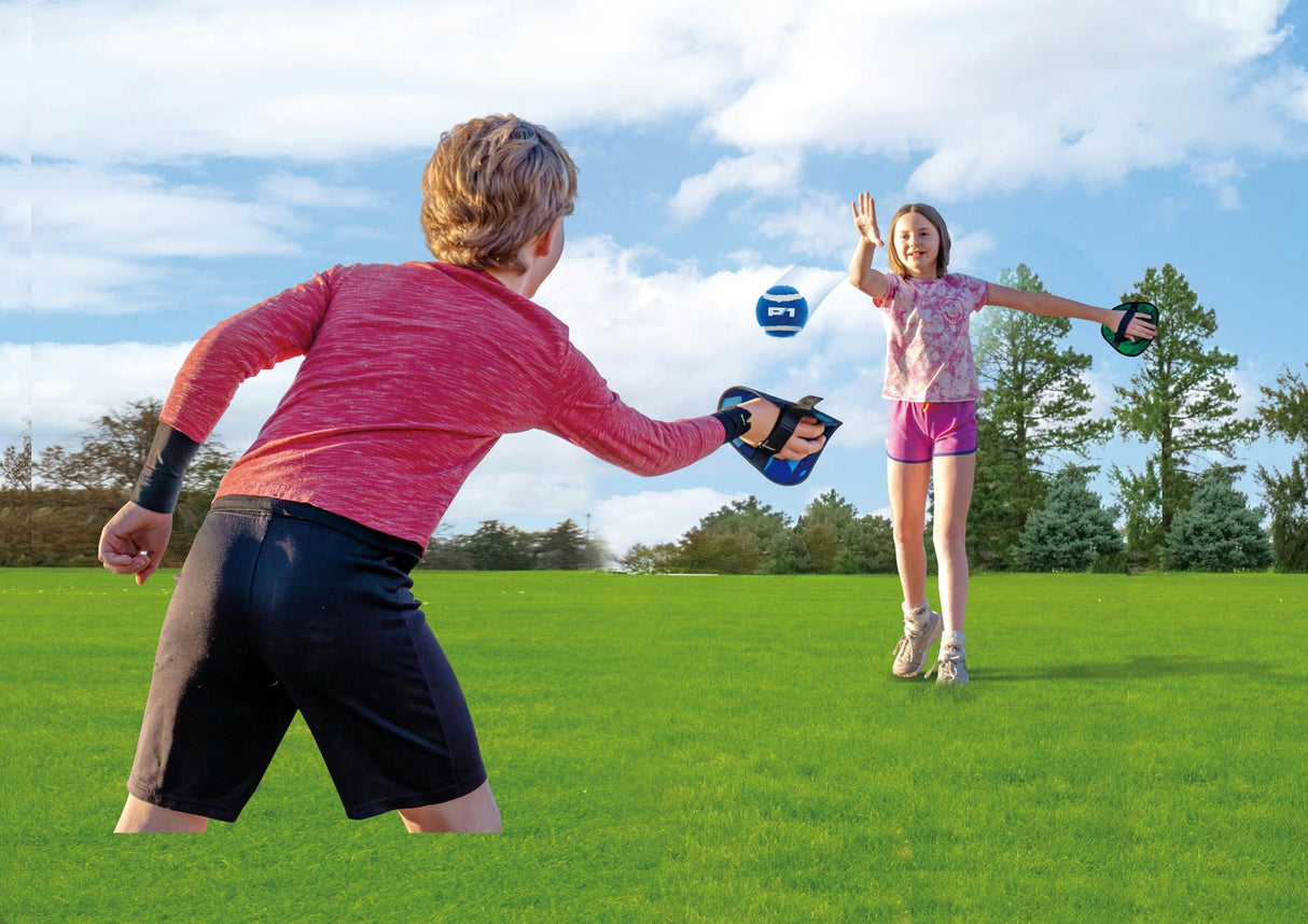 Two children playing with a Toss & Catch Ball Game that includes a blue ball on a grassy field under a clear sky.