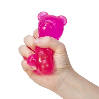 Hand holding a pink Nee Doh Gummy Bear stress reliever toy against a white background