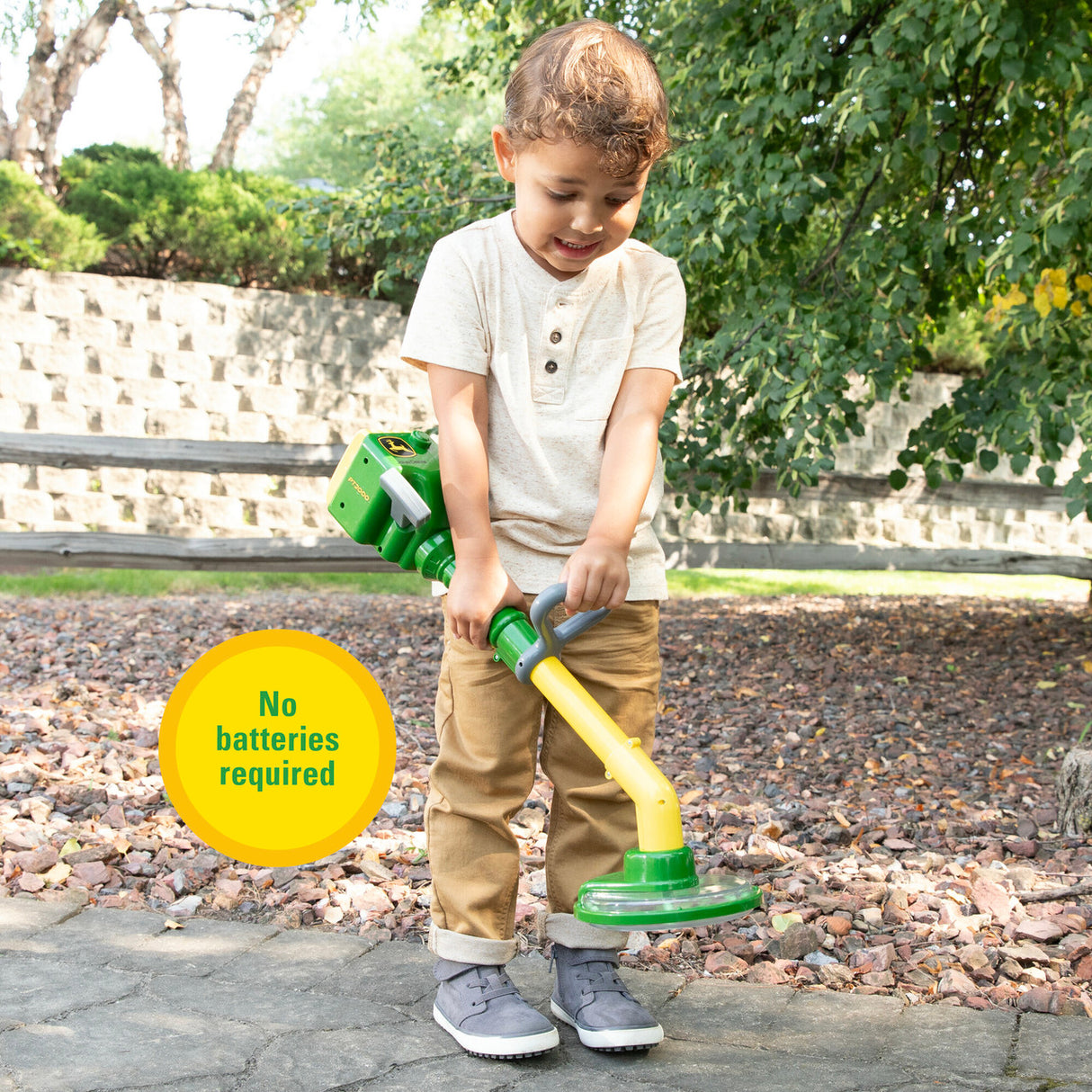 Child playing with a John Deere Weed Trimmer Toy outdoors