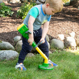 Child playing with a John Deere Weed Trimmer Toy in a garden setting