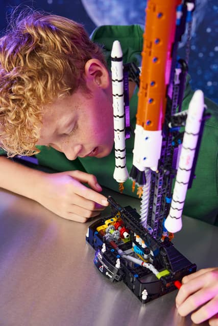Child playing with a LEGO Technic: NASA Artemis Space Launch System Rocket made from building blocks.