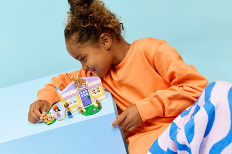 Child playing with a LEGO Friends: Heartlake City Bunny Hotel set on a light blue background