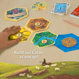Board game setup with cards and a landscape illustration, featuring text 'Build out Catan as you go!'.