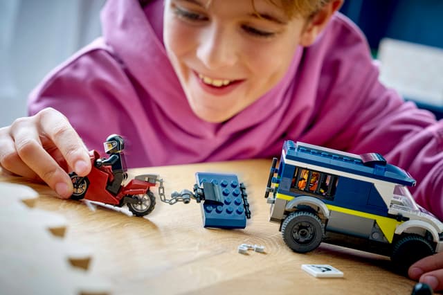 Child playing with a LEGO City Police: Police Prisoner Transport Van on a wooden table
