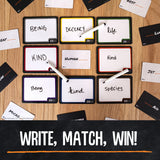 A flat-lay view of a word-matching Blank Slate™ Game board on a wooden surface, with black cards, white writing markers, and several white cards partially visible around the board. A black banner at the bottom reads “WRITE, MATCH, WIN!” in white text.