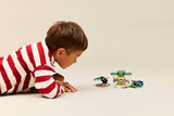 Child playing with LEGO Star Wars: Grogu's Homestead figures on a plain background