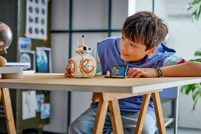 Child playing with a LEGO Star Wars: BB-8™ Astromech Droid at a table in a modern room.